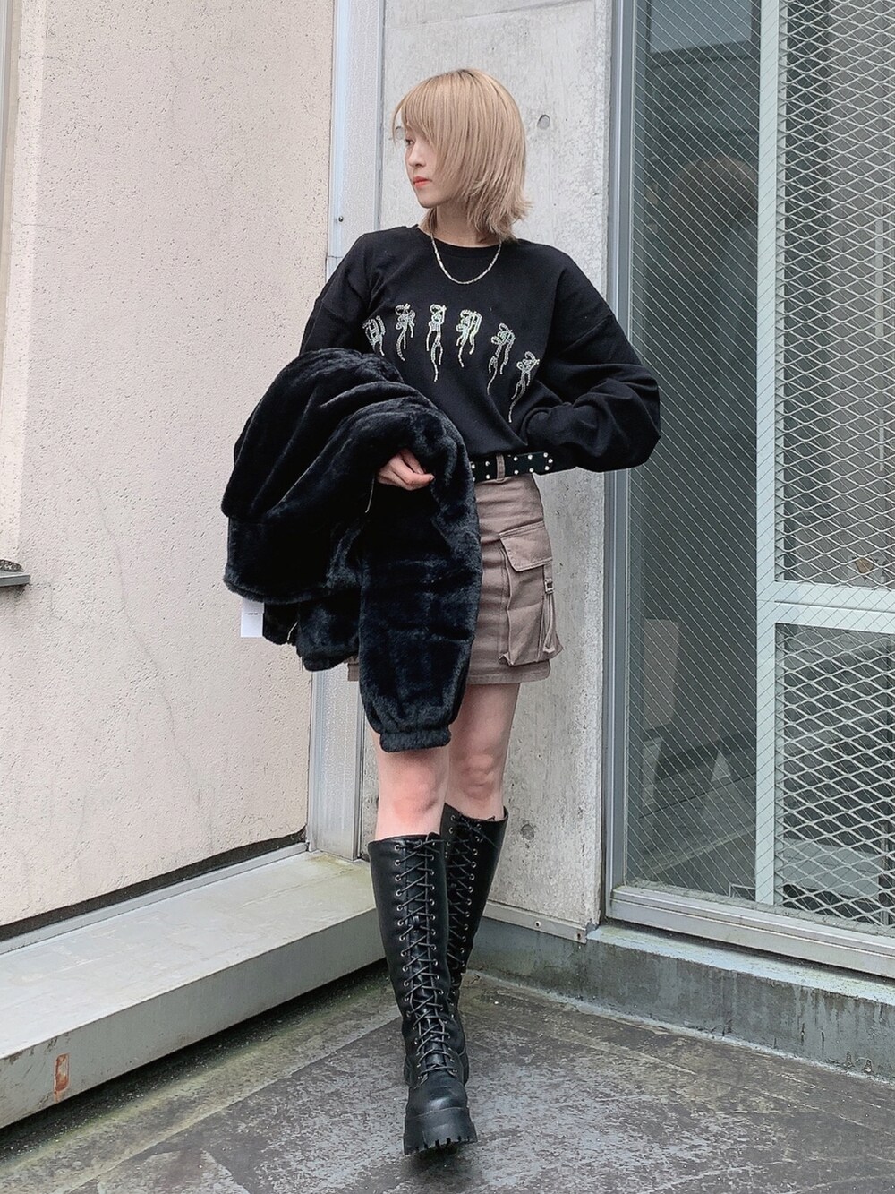 ブラック系のブルゾン、ブラック系のTシャツ/カットソー、グリーン系のスカートを着用したレディースの秋コーディネートの2枚目の写真