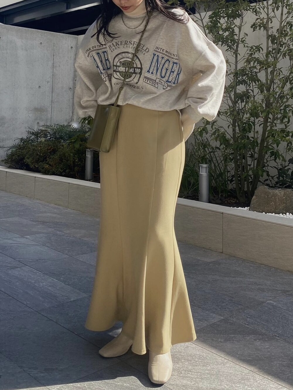 イエロー系のスカート、グレー系のスウェット、ホワイト系のニット/セーターを着用したレディースの冬コーディネートの2枚目の写真