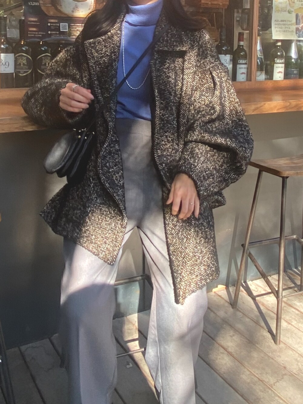 ブルー系のニット/セーター、ブラック系のその他アウター、グレー系のスラックスを着用したレディースの冬コーディネートの2枚目の写真