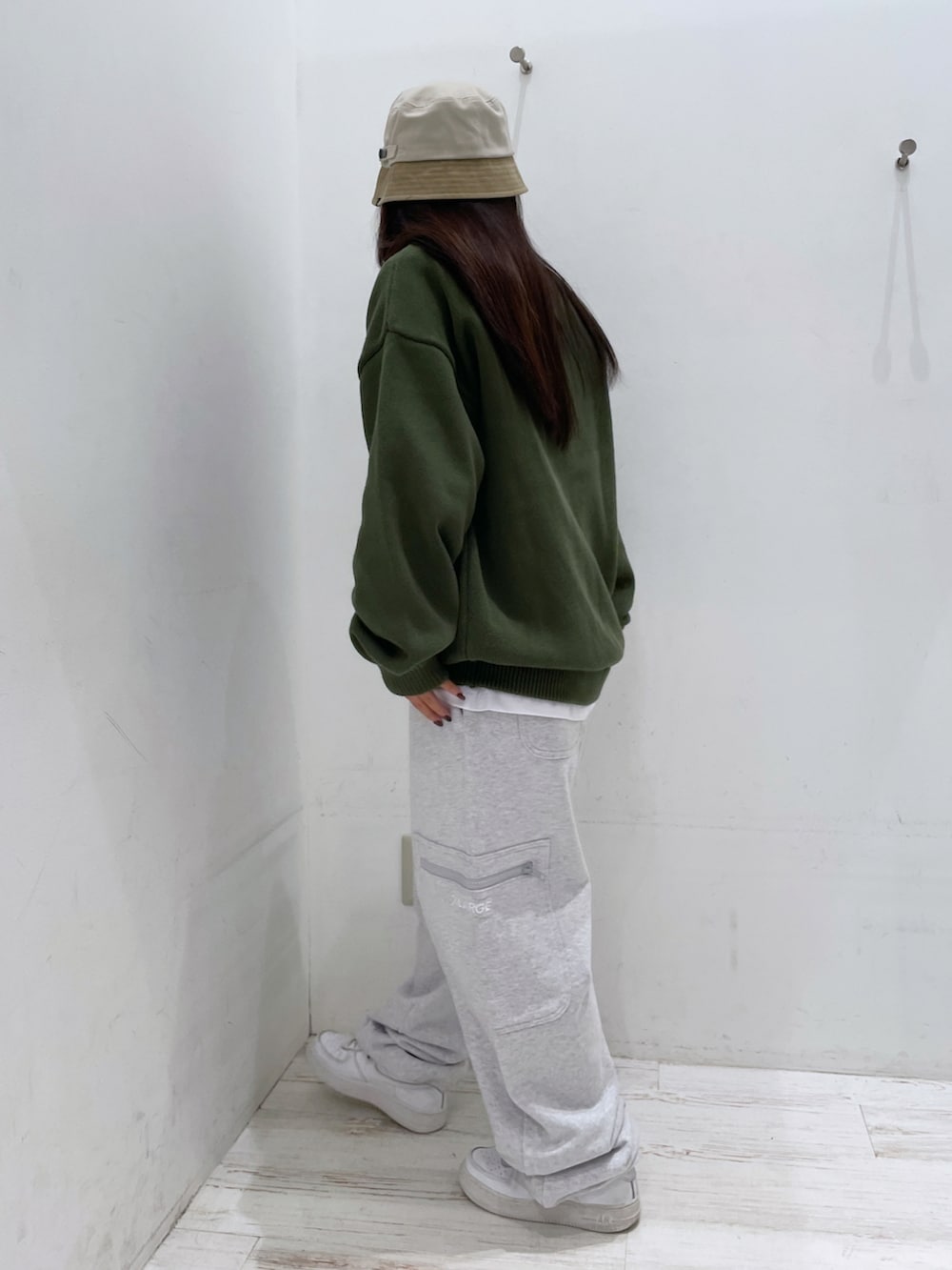 グレー系のスウェットパンツ、グリーン系のニット/セーター、ベージュ系のハットを着用したレディースの秋コーディネートの2枚目の写真