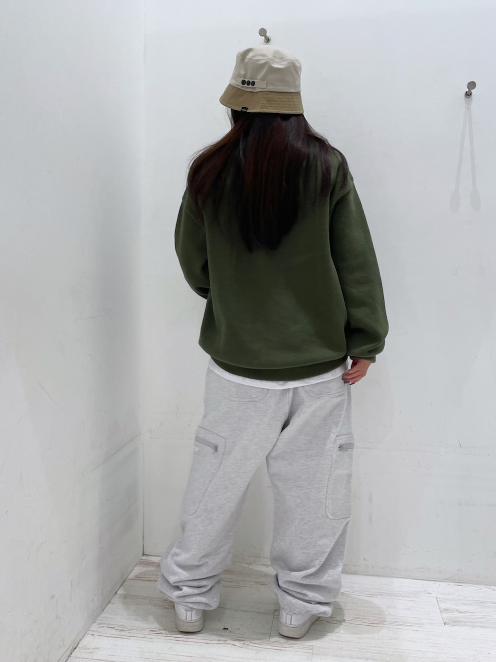 グレー系のスウェットパンツ、グリーン系のニット/セーター、ベージュ系のハットを着用したレディースの秋コーディネートの3枚目の写真