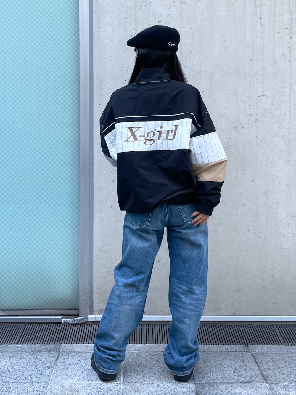 ブラック系のブルゾン、ブルー系のデニムパンツ、ブラック系のハンチング/ベレー帽を着用したレディースの冬コーディネートの2枚目の写真