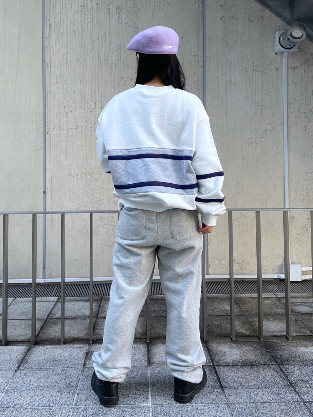 グレー系のスウェットパンツ、ホワイト系のスウェット、パープル系のハンチング/ベレー帽を着用したレディースの冬コーディネートの2枚目の写真