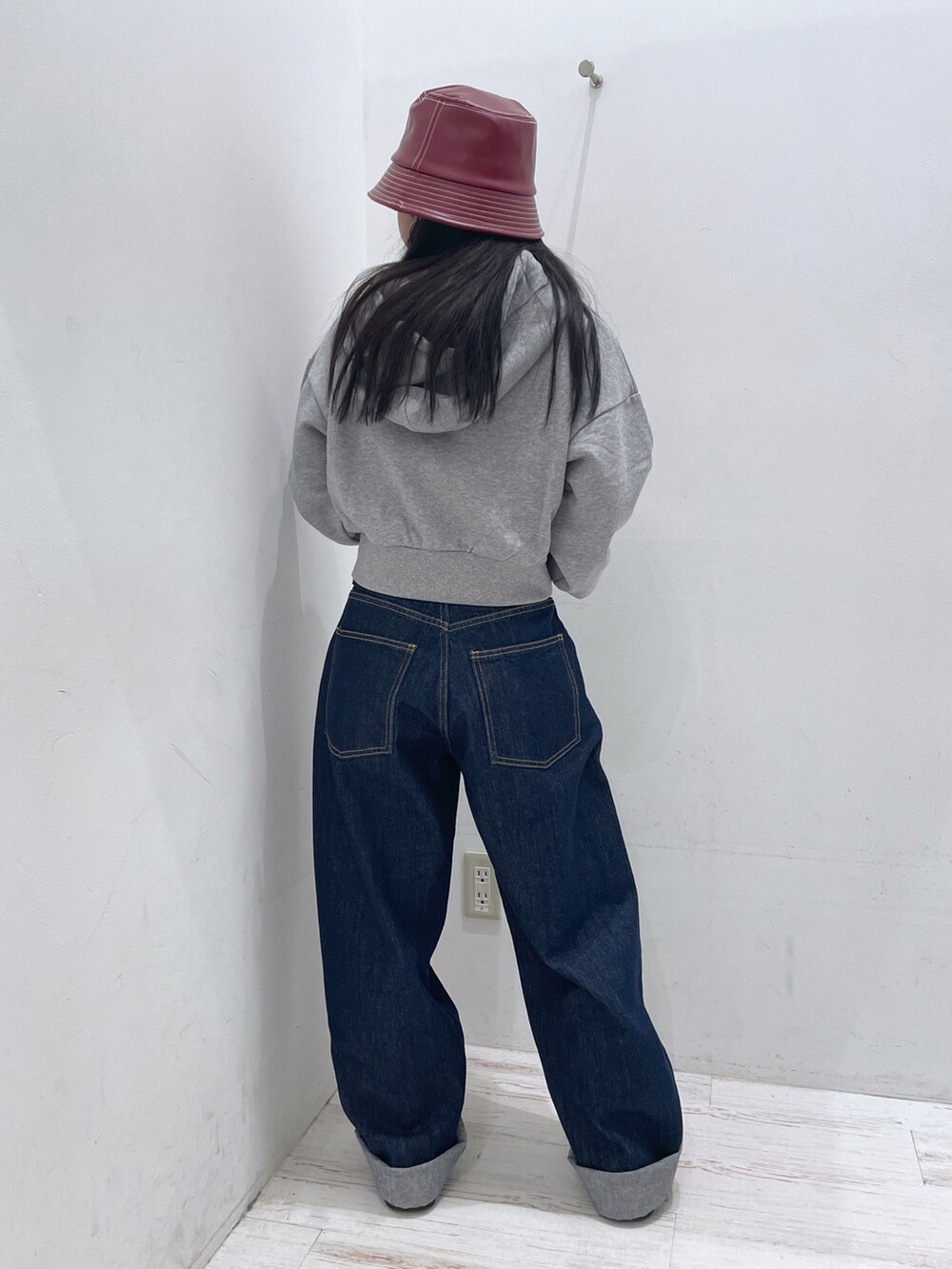 ブルー系のデニムパンツ、グレー系のパーカー、レッド系のハットを着用したレディースの秋コーディネートの2枚目の写真