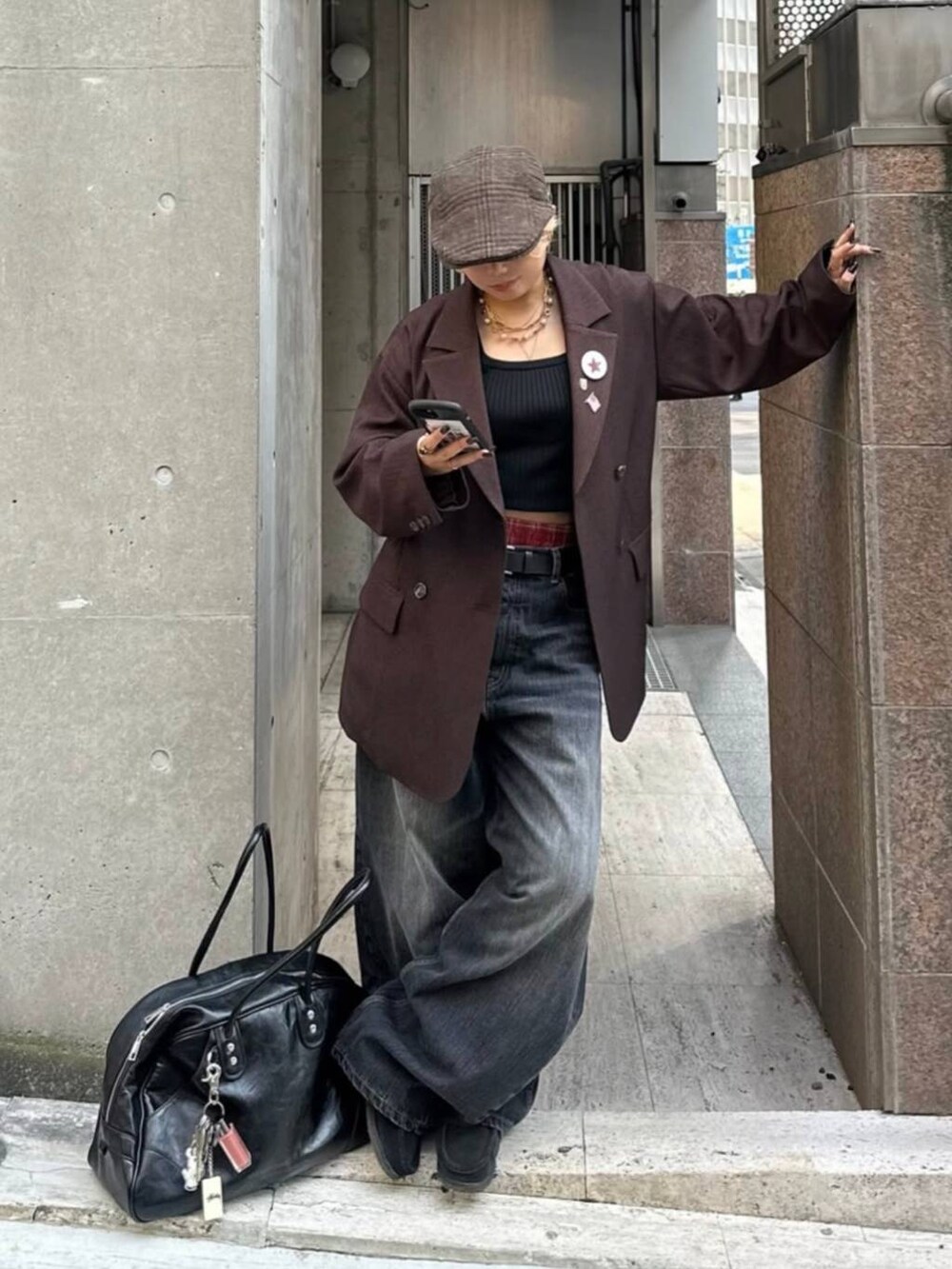 ブラック系のボストンバッグ、ブラウン系のテーラードジャケット、ブラック系のデニムパンツを着用したレディースの秋コーディネートの2枚目の写真