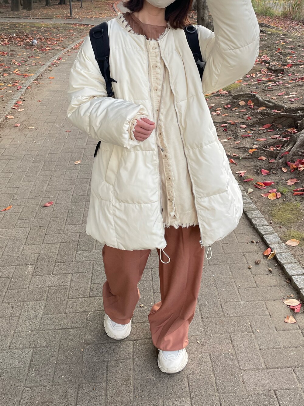 ピンク系のスラックス、ベージュ系のスニーカー、ホワイト系のブルゾンを着用したレディースの秋コーディネートの2枚目の写真