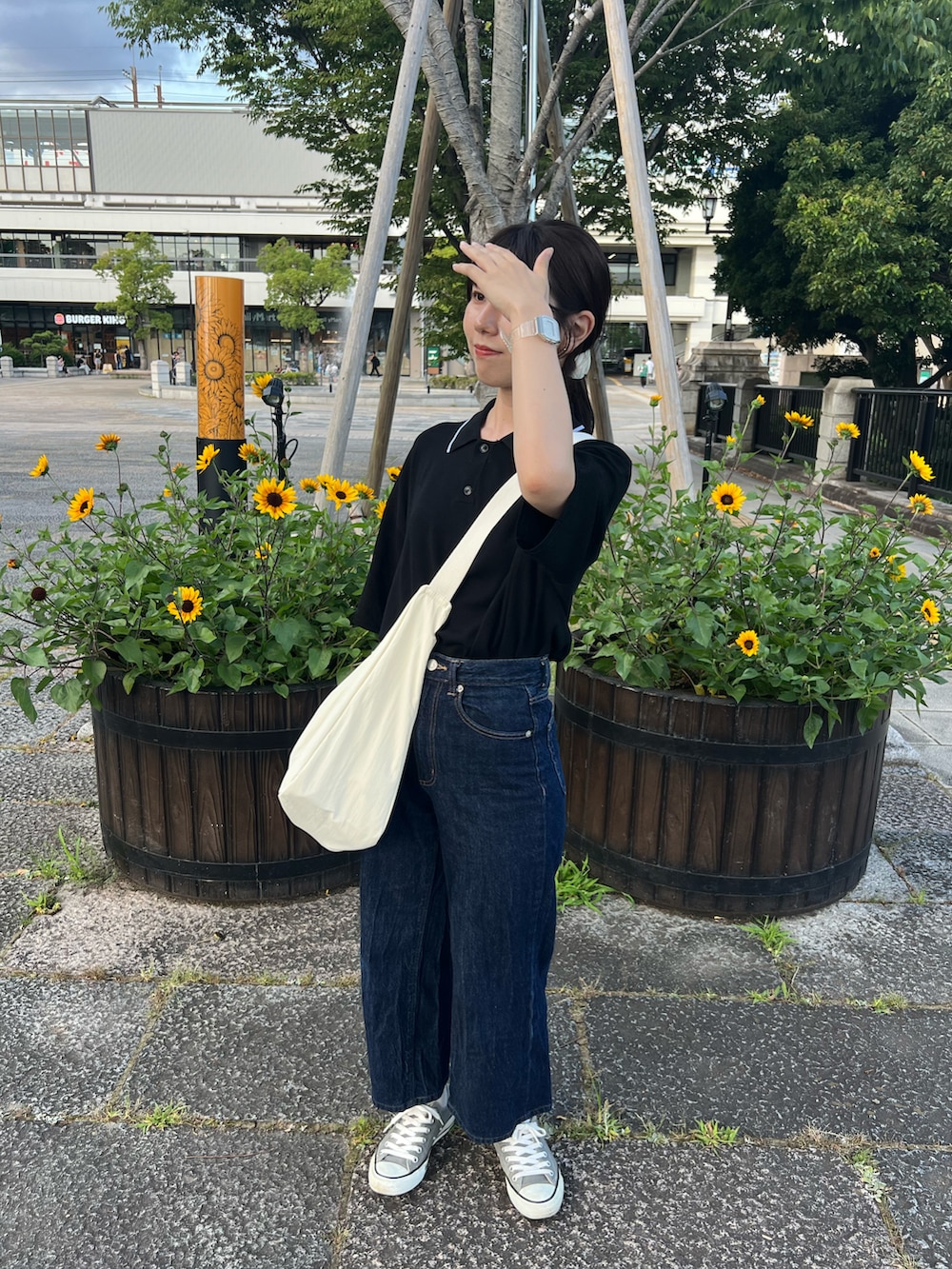 ブルー系のデニムパンツ、ホワイト系のショルダーバッグ、グレー系のスニーカーを着用したレディースの夏コーディネートの3枚目の写真