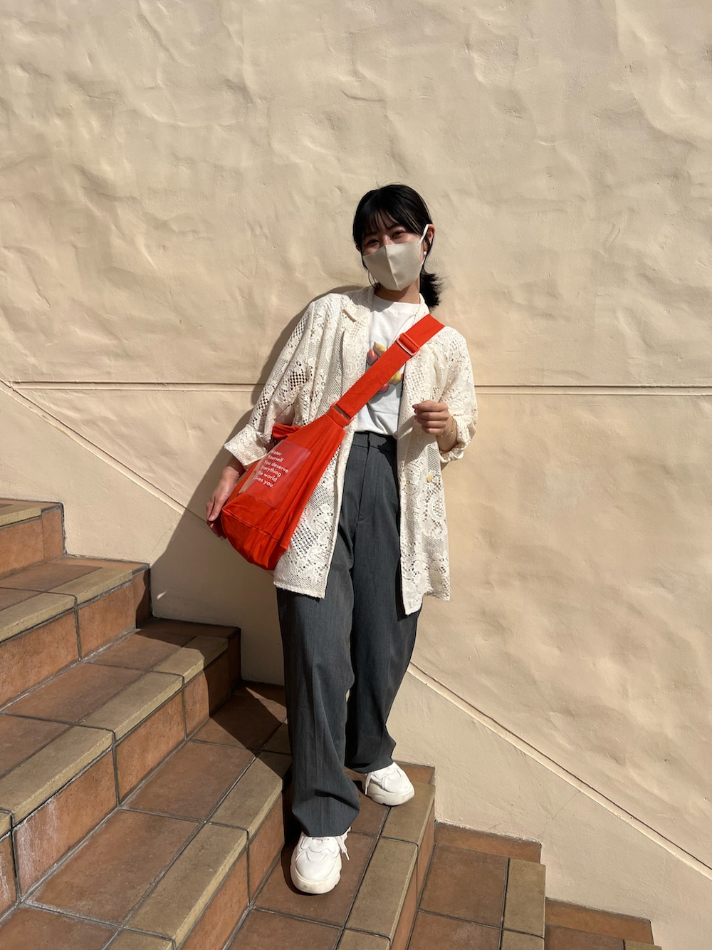 オレンジ系のショルダーバッグ、ホワイト系のTシャツ/カットソー、ホワイト系のテーラードジャケットを着用したレディースの春コーディネートの2枚目の写真