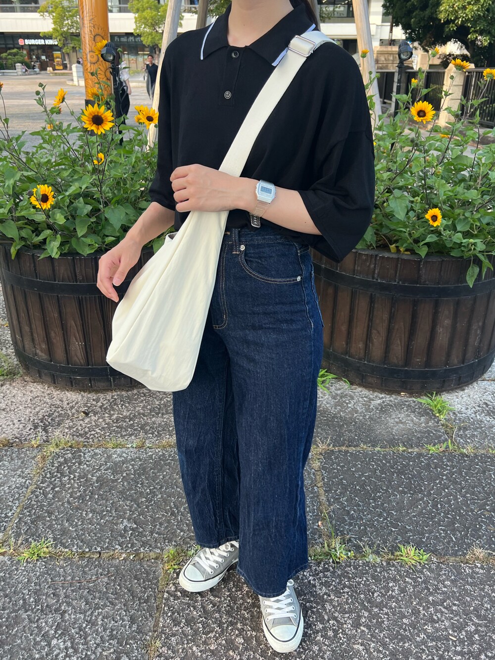 ブルー系のデニムパンツ、ホワイト系のショルダーバッグ、グレー系のスニーカーを着用したレディースの夏コーディネートの2枚目の写真