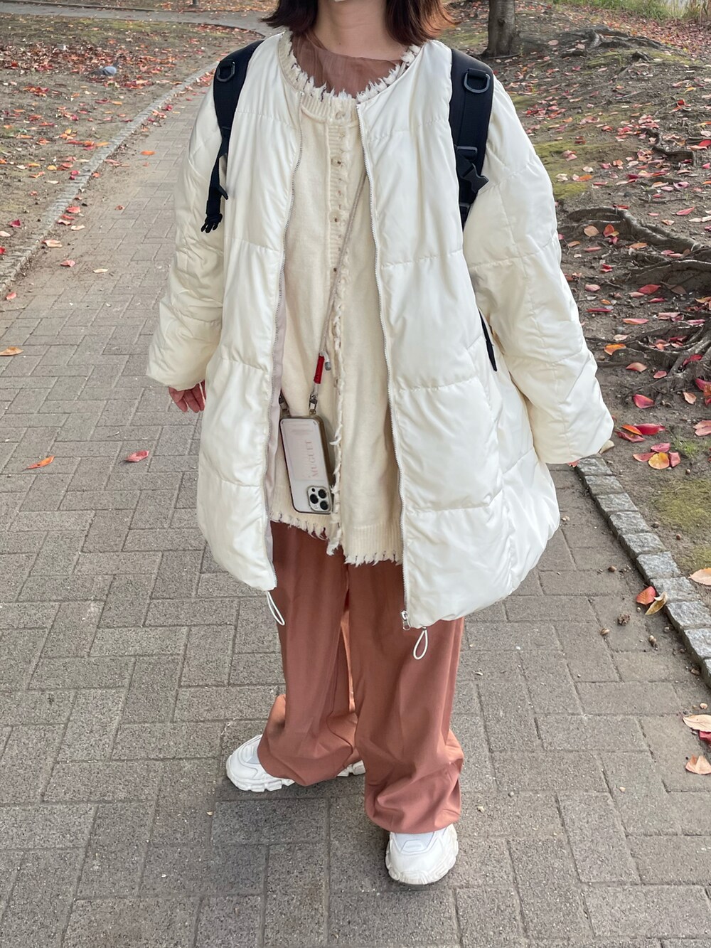 ピンク系のスラックス、ベージュ系のスニーカー、ホワイト系のブルゾンを着用したレディースの秋コーディネートの3枚目の写真