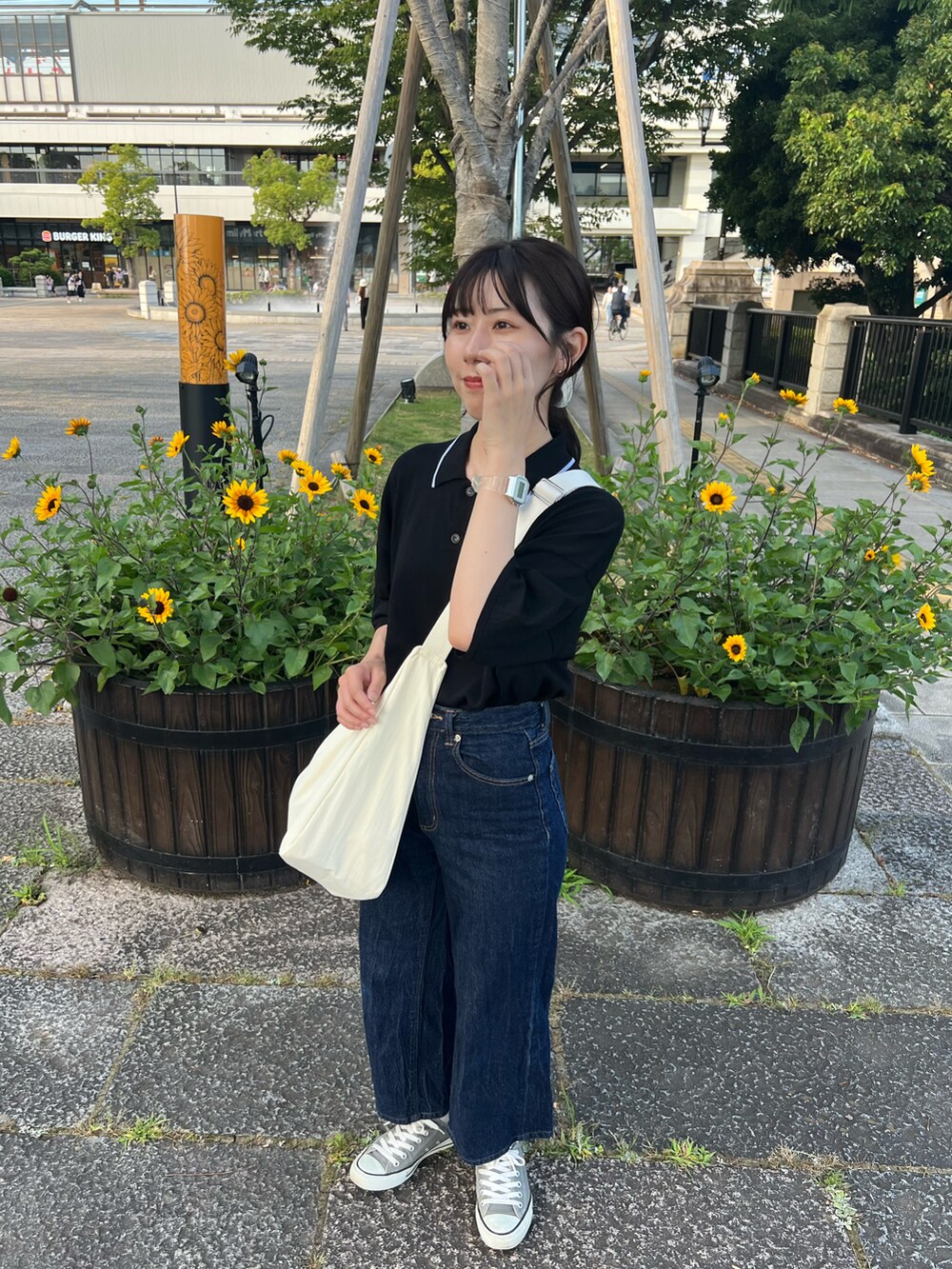 ブルー系のデニムパンツ、ホワイト系のショルダーバッグ、グレー系のスニーカーを着用したレディースの夏コーディネートの4枚目の写真