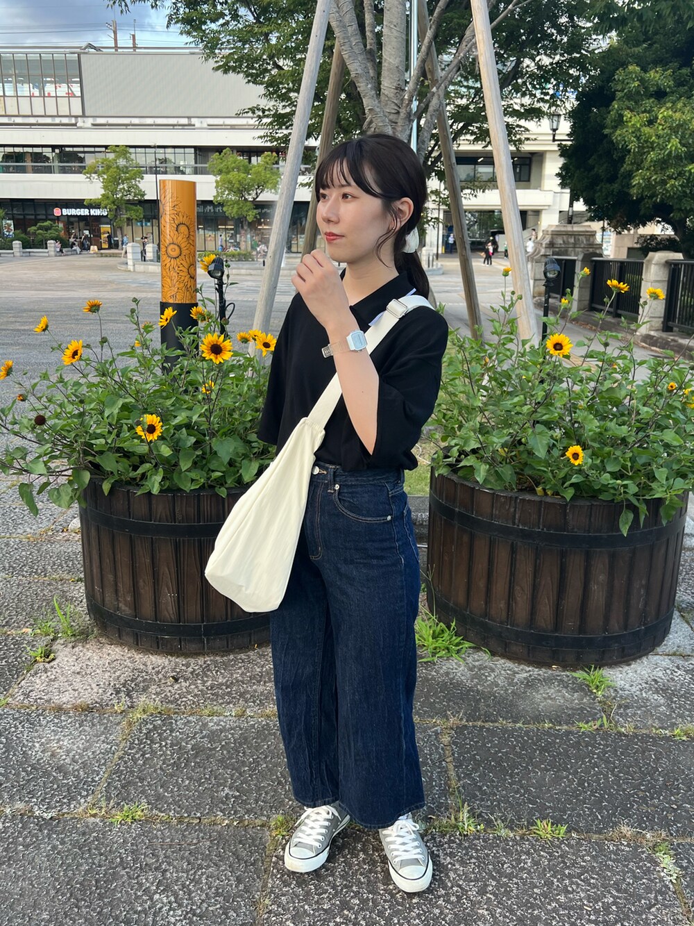 ブルー系のデニムパンツ、ホワイト系のショルダーバッグ、グレー系のスニーカーを着用したレディースの夏コーディネートの5枚目の写真