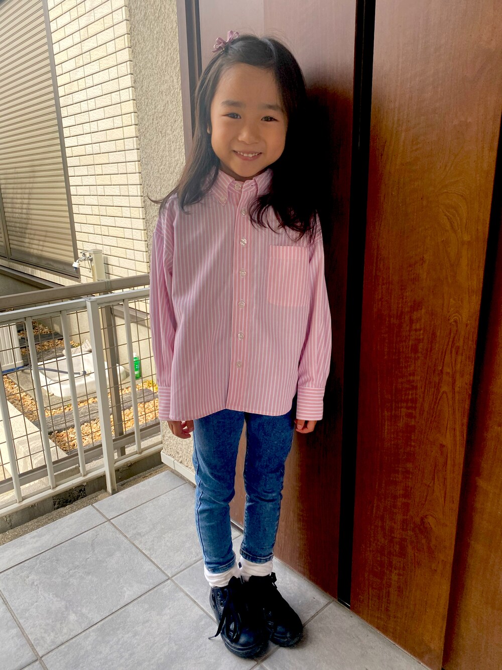 ピンク系のシャツ/ブラウス、ブルー系のデニムパンツ、ブラック系のスニーカーを着用したキッズの春コーディネートの2枚目の写真