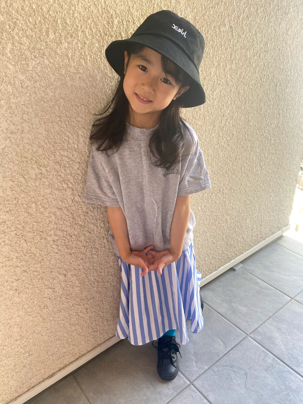 グレー系のTシャツ/カットソー、ブルー系のスカート、ブラック系のスニーカーを着用したキッズの春コーディネートの2枚目の写真