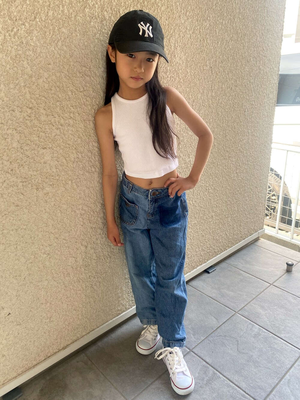 ホワイト系のタンクトップ、ブルー系のデニムパンツ、ホワイト系のスニーカーを着用したキッズの夏コーディネートの2枚目の写真