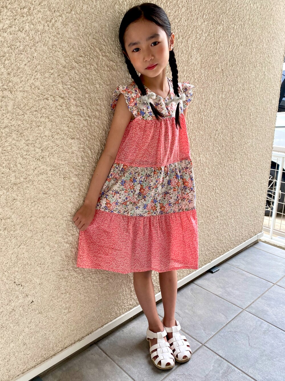 ピンク系のワンピース、ホワイト系のサンダルを着用したキッズの夏コーディネートの2枚目の写真