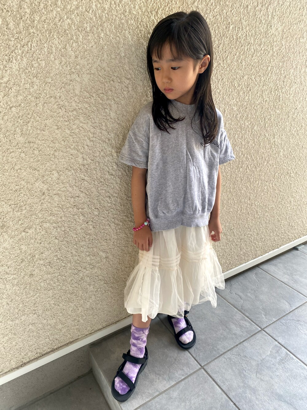 グレー系のTシャツ/カットソー、ホワイト系のスカート、ブラック系のサンダルを着用したキッズの秋コーディネートの2枚目の写真