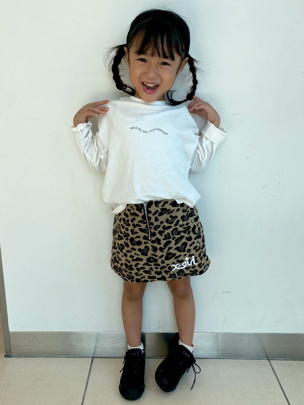 ベージュ系のスカート、ホワイト系のTシャツ/カットソー、ブラック系のスニーカーを着用したキッズの秋コーディネートの2枚目の写真