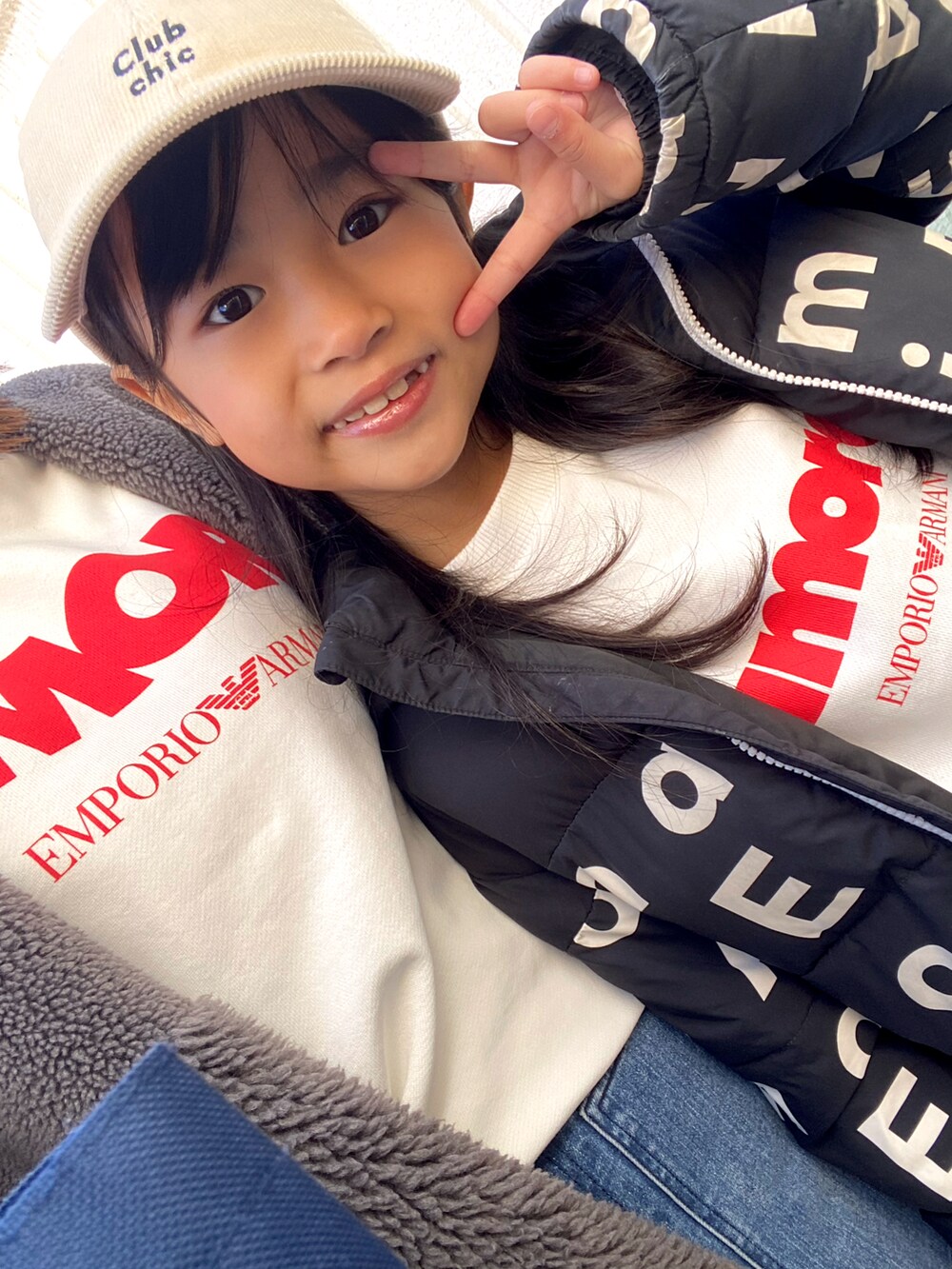 ホワイト系のトップス、ブルー系のデニムパンツ、ブラック系のスニーカーを着用したキッズの冬コーディネートの3枚目の写真