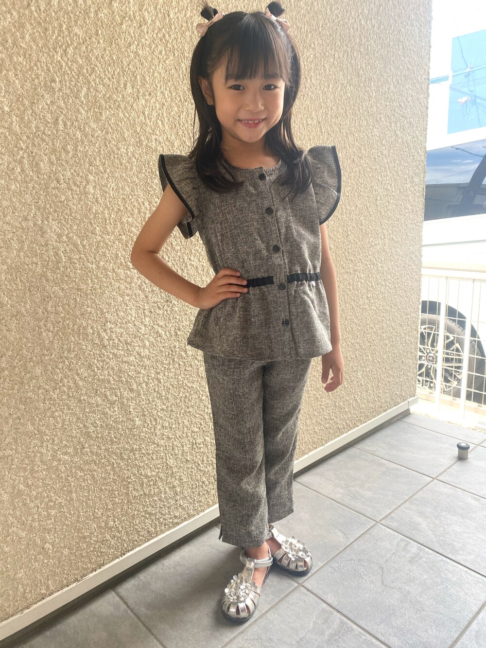 シルバー系のサンダル、ブラック系のセットアップを着用したキッズの夏コーディネートの2枚目の写真