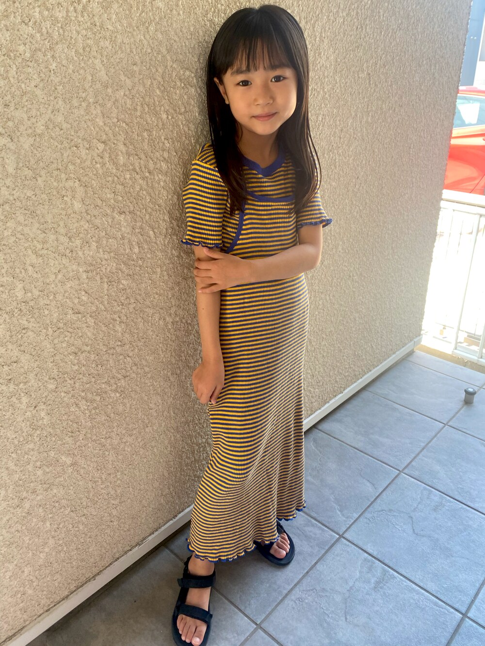 ブルー系のワンピース、ブラック系のサンダルを着用したキッズの夏コーディネートの2枚目の写真