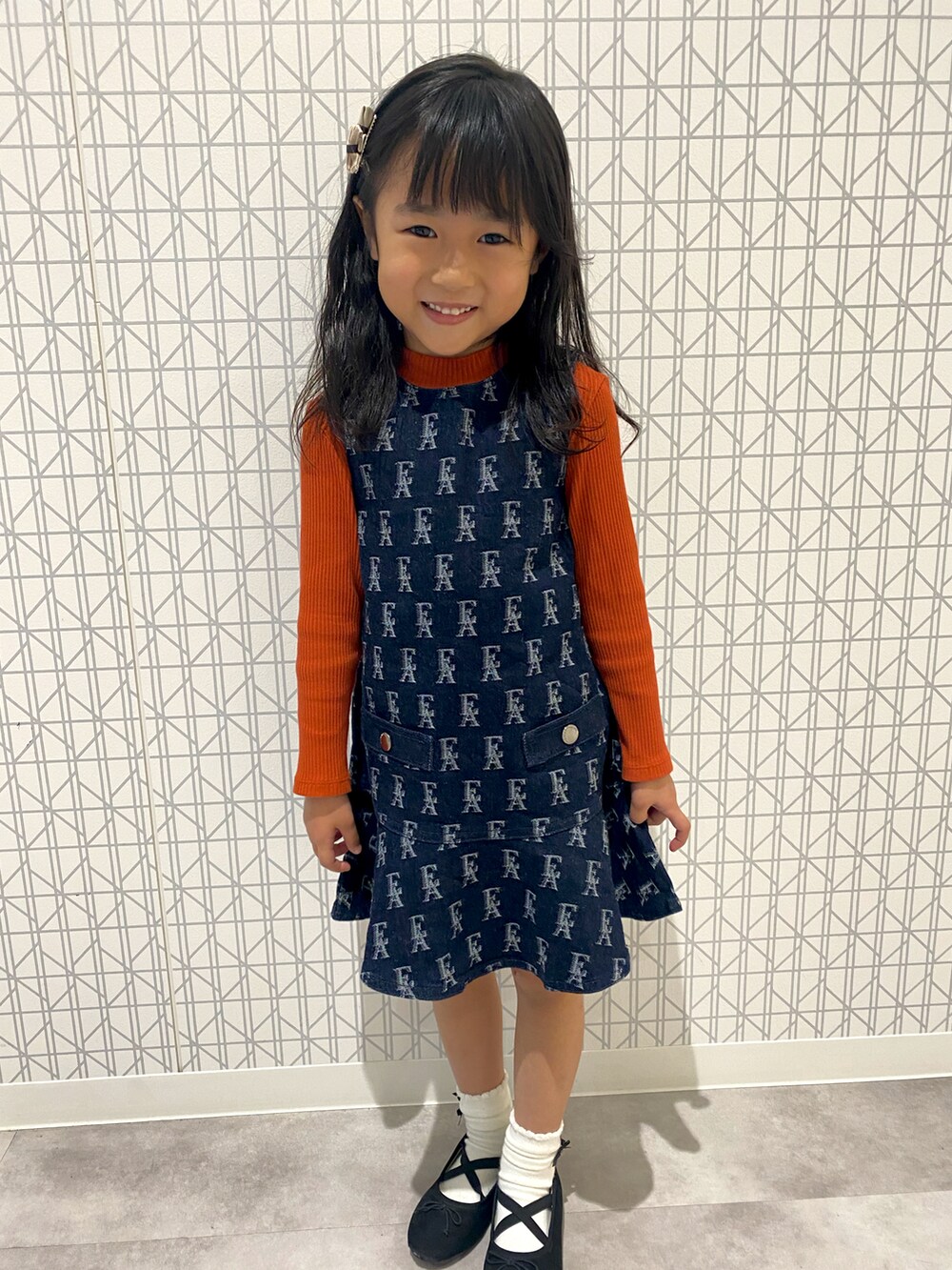 ブルー系のワンピース/ドレス、オレンジ系のトップス、ブラック系のバレエシューズを着用したキッズの秋コーディネートの2枚目の写真