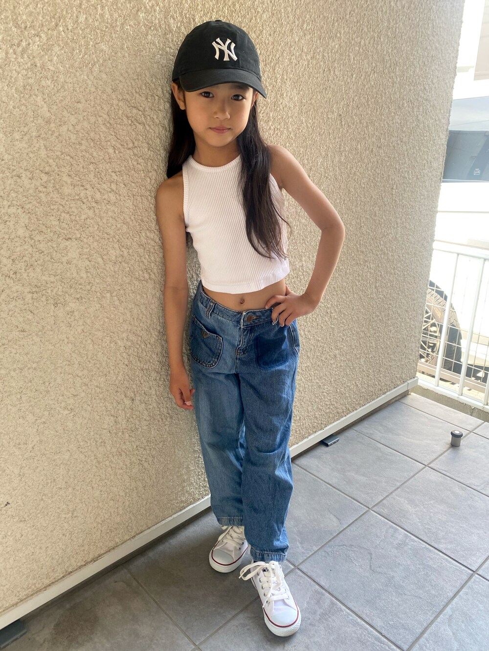 ホワイト系のタンクトップ、ブルー系のデニムパンツ、ホワイト系のスニーカーを着用したキッズの夏コーディネートの3枚目の写真