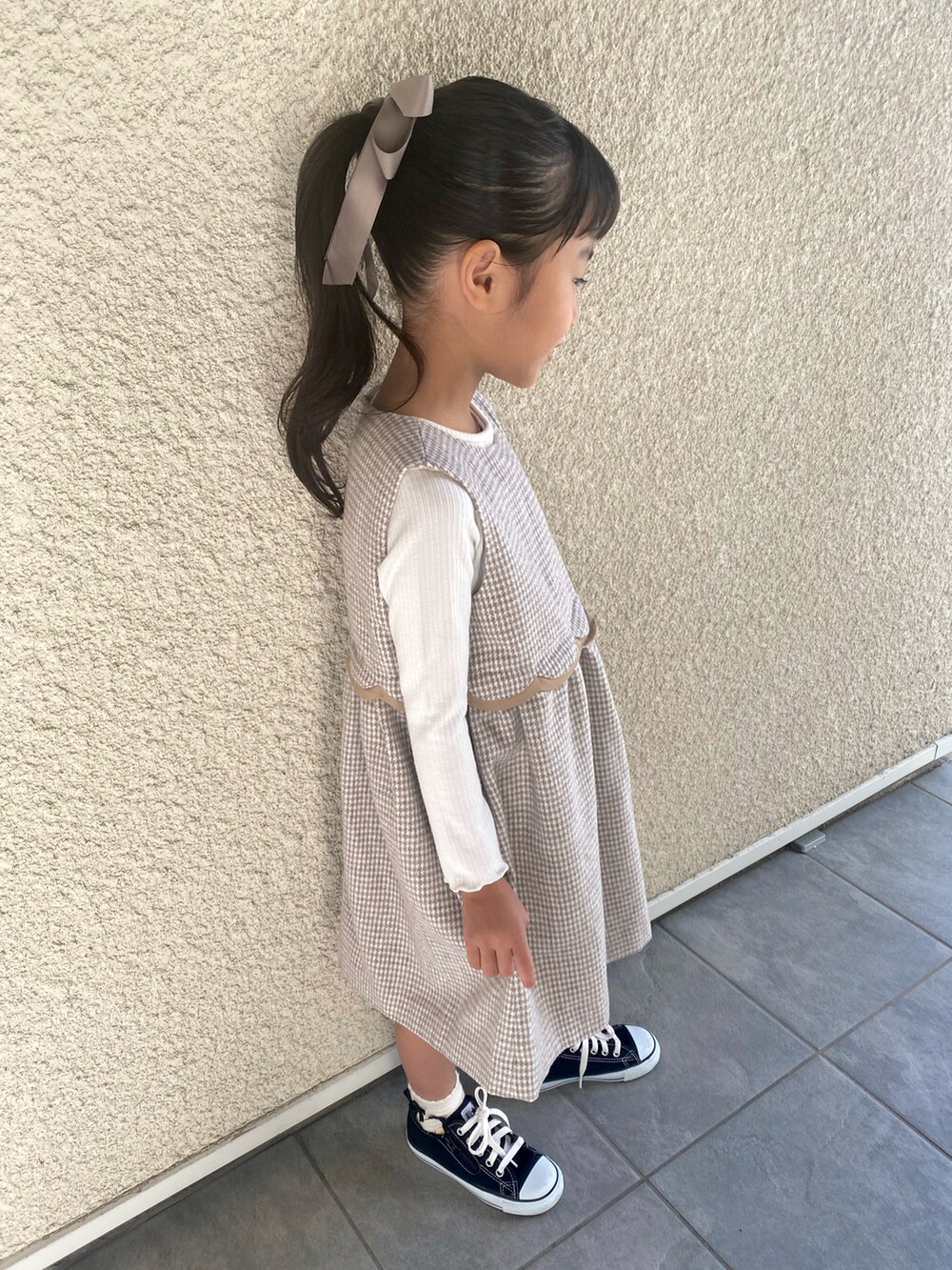 ベージュ系のワンピース、ホワイト系のTシャツ/カットソー、ブラック系のスニーカーを着用したキッズの秋コーディネートの3枚目の写真