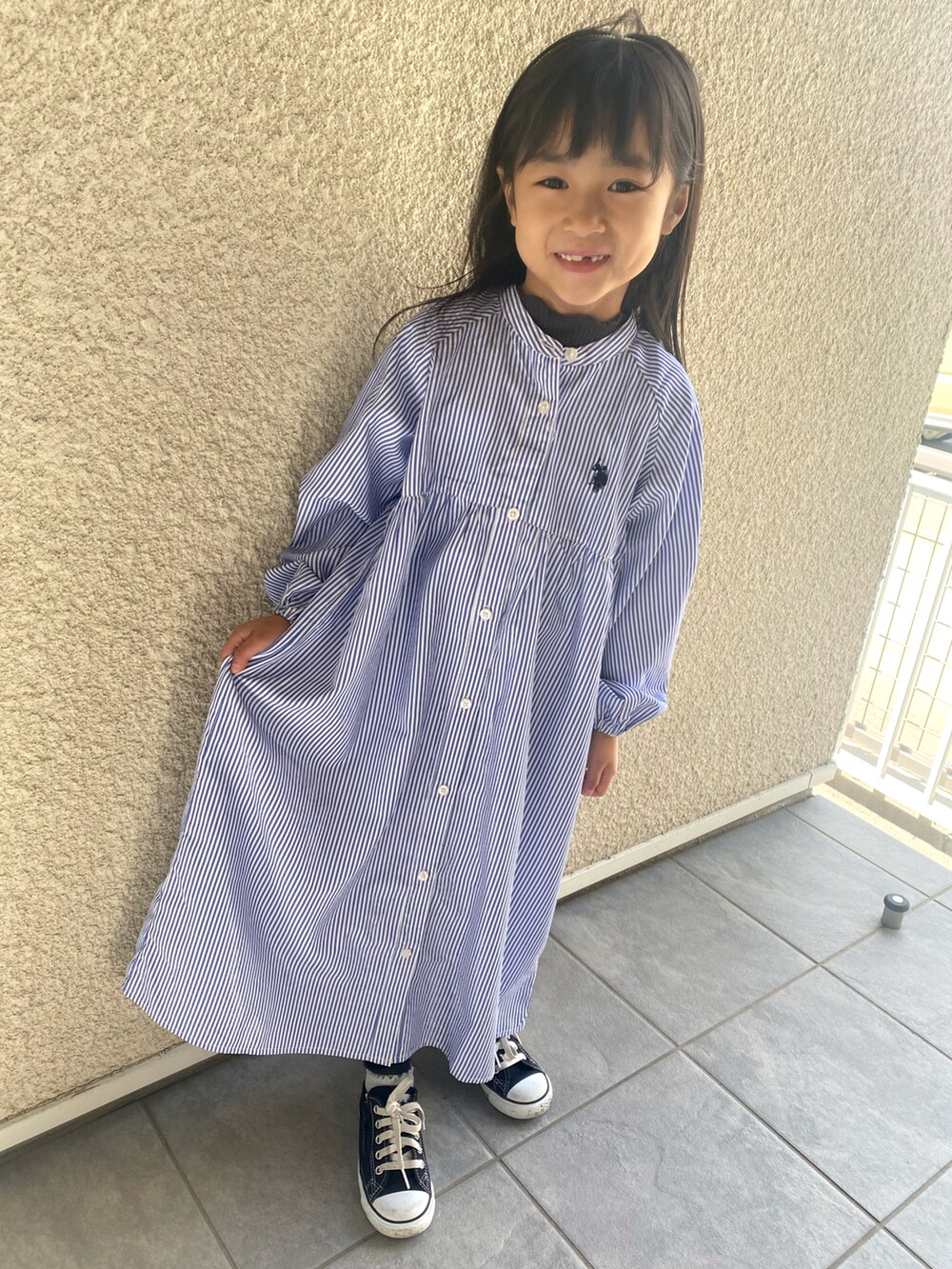 ブルー系のシャツワンピース、ブラック系のスニーカー、ホワイト系のカチューシャを着用したキッズの春コーディネートの2枚目の写真
