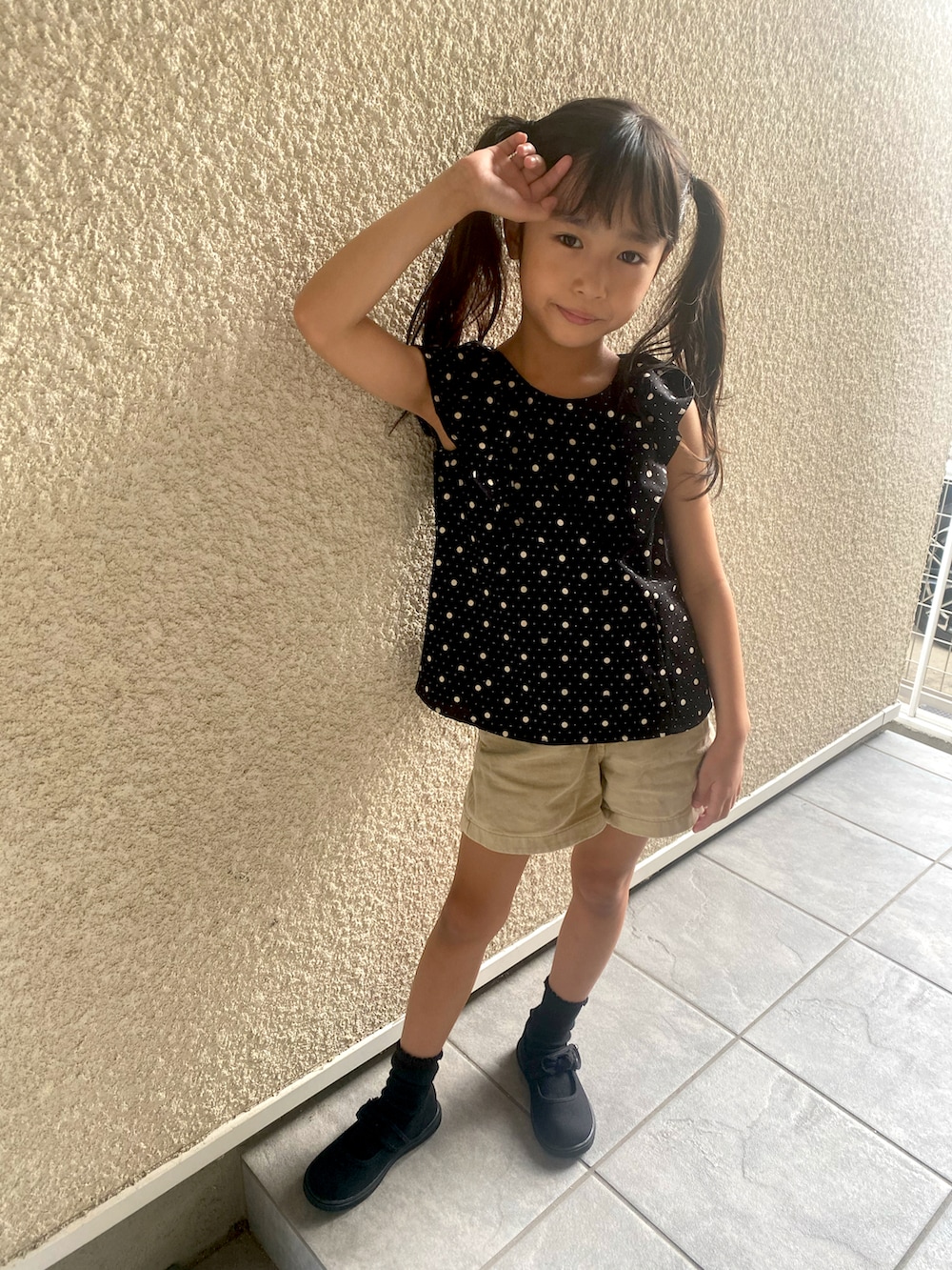 ブラック系のトップス、ベージュ系のパンツ、ブラック系のスニーカーを着用したキッズの秋コーディネートの3枚目の写真