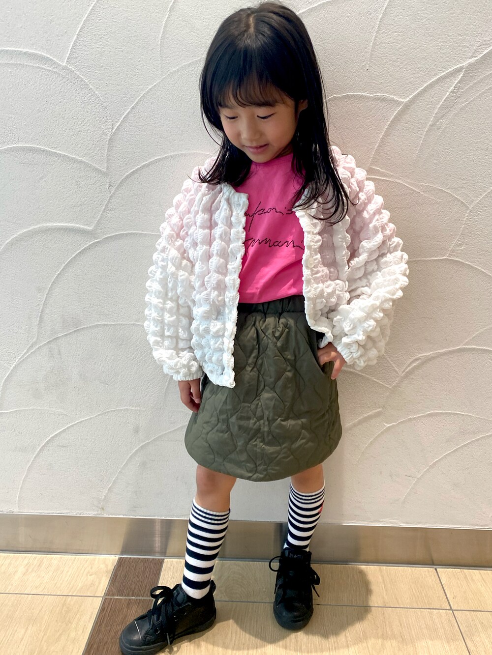 ピンク系のTシャツ/カットソー、ホワイト系のカーディガン/ボレロ、グリーン系のスカートを着用したキッズの春コーディネートの2枚目の写真