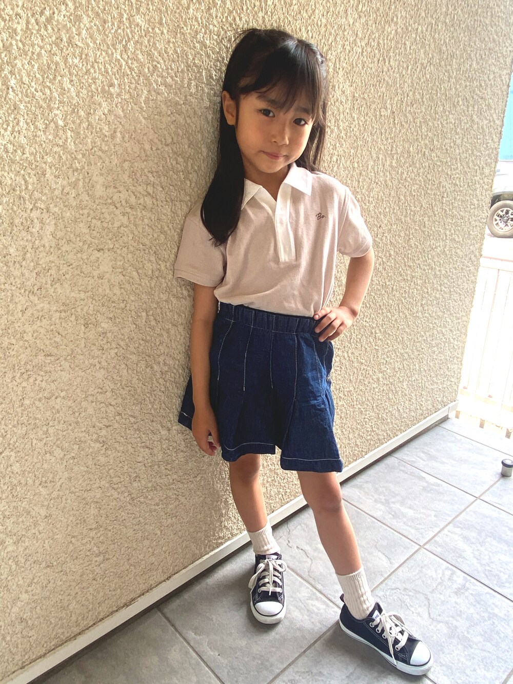 ベージュ系のポロシャツ、ブルー系のデニムスカート、ブラック系のスニーカーを着用したキッズの夏コーディネートの2枚目の写真