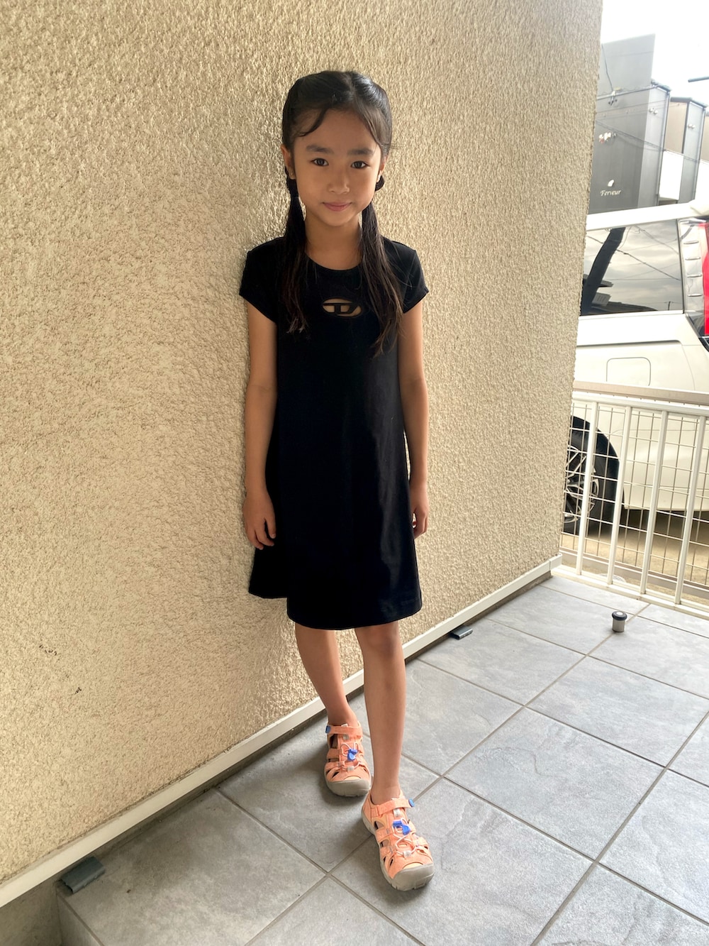 ブラック系のワンピース、ピンク系のサンダルを着用したキッズの夏コーディネートの2枚目の写真