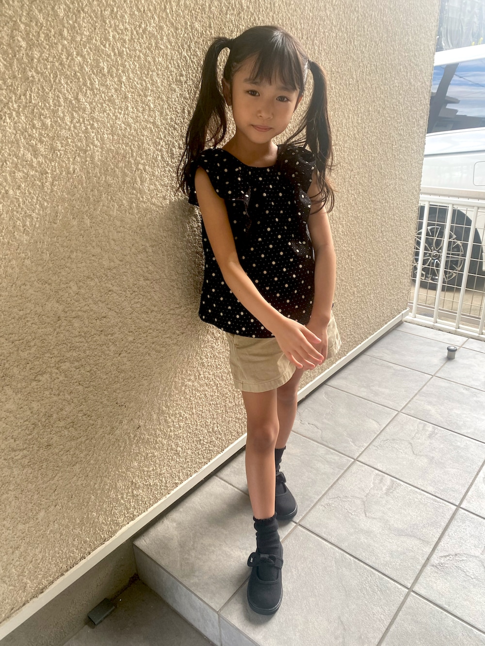 ブラック系のトップス、ベージュ系のパンツ、ブラック系のスニーカーを着用したキッズの秋コーディネートの2枚目の写真