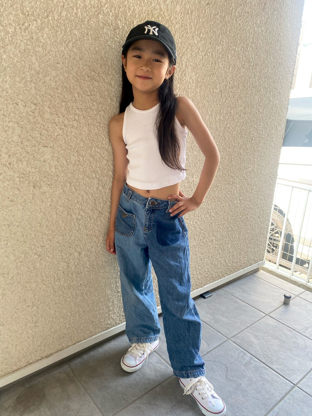 ホワイト系のタンクトップ、ブルー系のデニムパンツ、ホワイト系のスニーカーを着用したキッズの夏コーディネートの4枚目の写真
