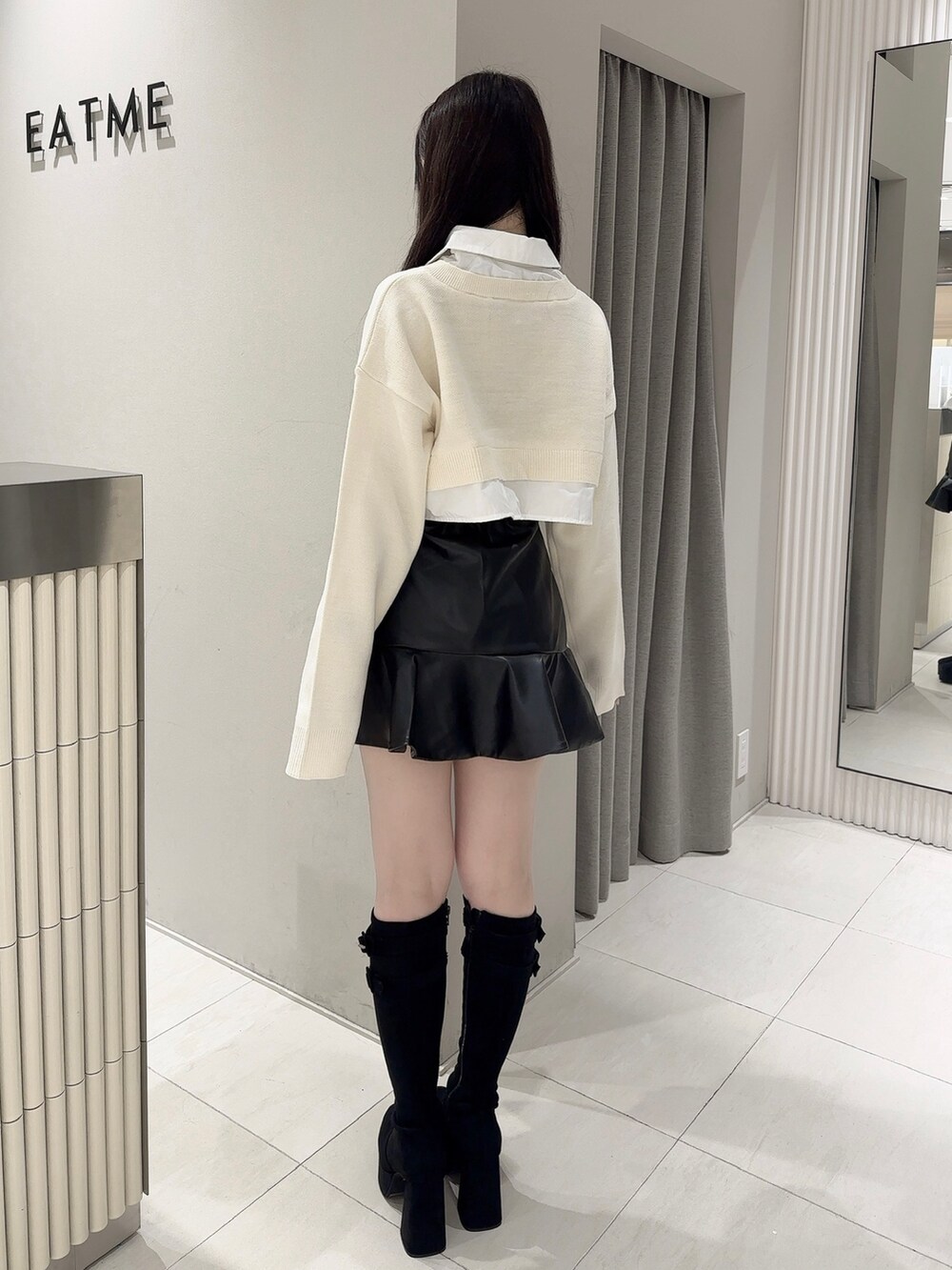 ブラック系のスカート、ホワイト系のシャツ/ブラウス、ブラック系のブーツを着用したレディースの秋コーディネートの3枚目の写真