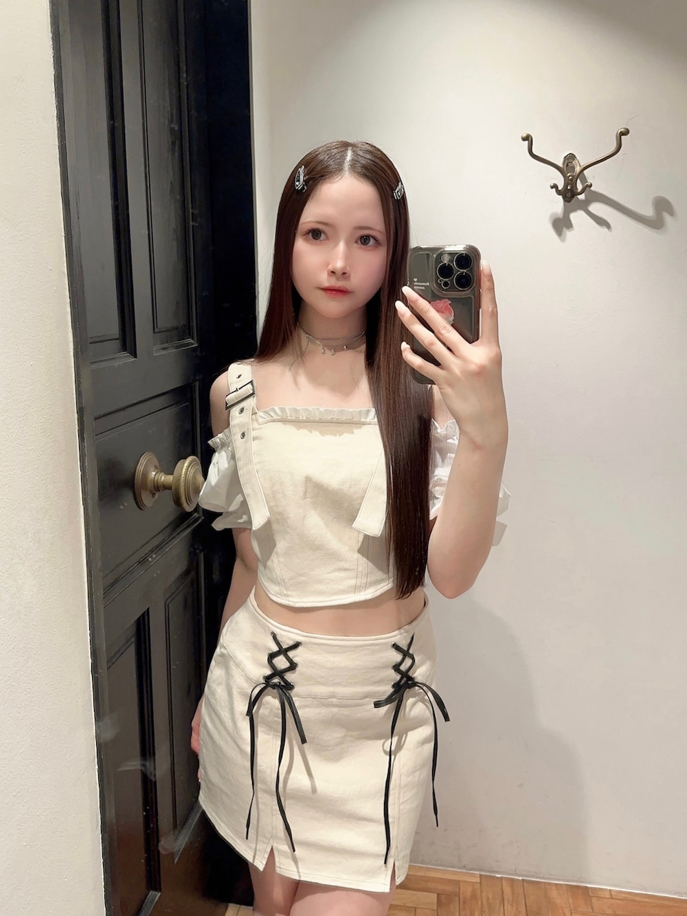 ホワイト系のベスト、ホワイト系のデニムスカート、ブラック系のハンドバッグを着用したレディースの夏コーディネートの3枚目の写真