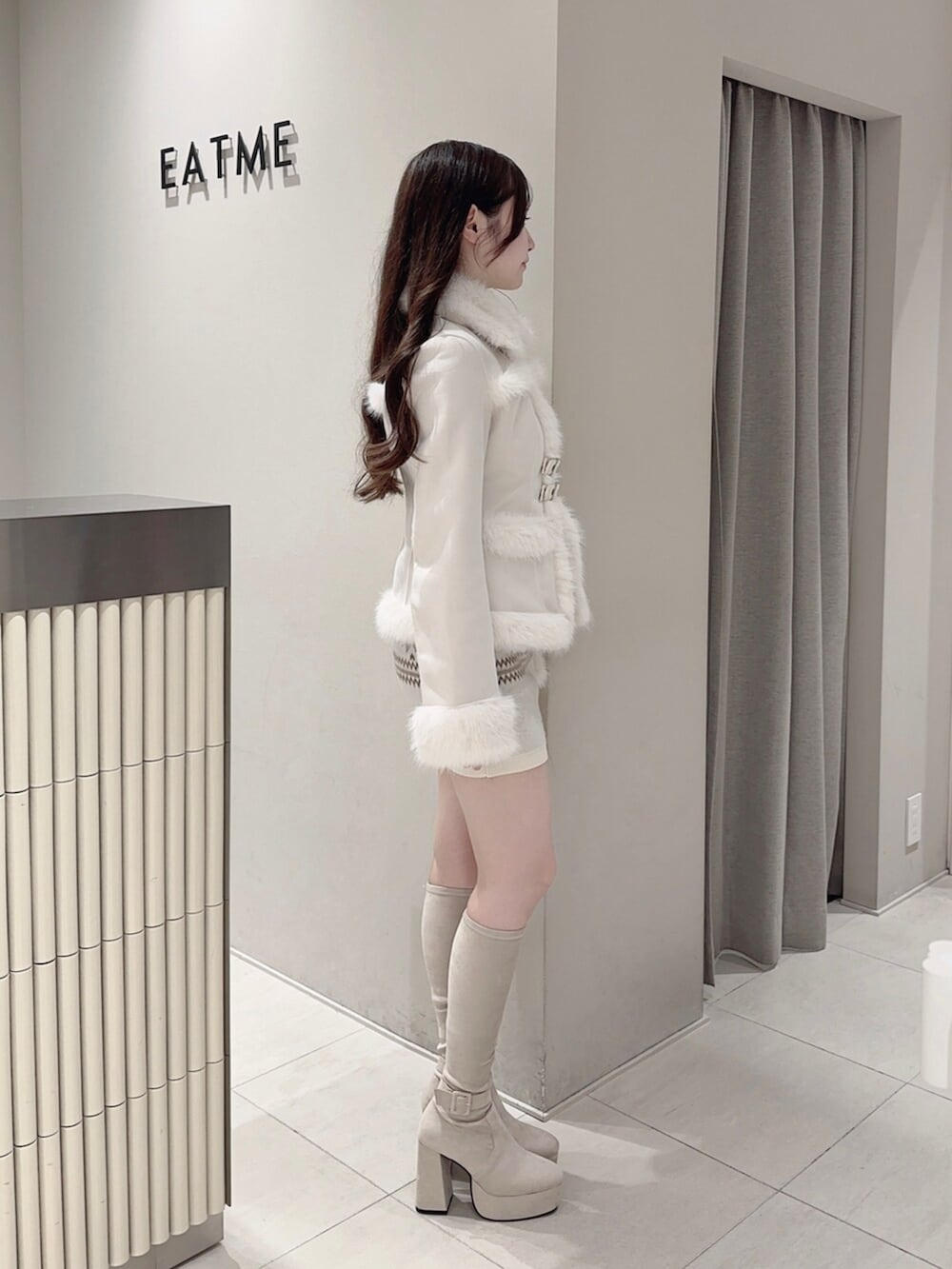 ブラウン系のショルダーバッグ、ホワイト系のブーツ、ホワイト系のスカートを着用したレディースの秋コーディネートの4枚目の写真