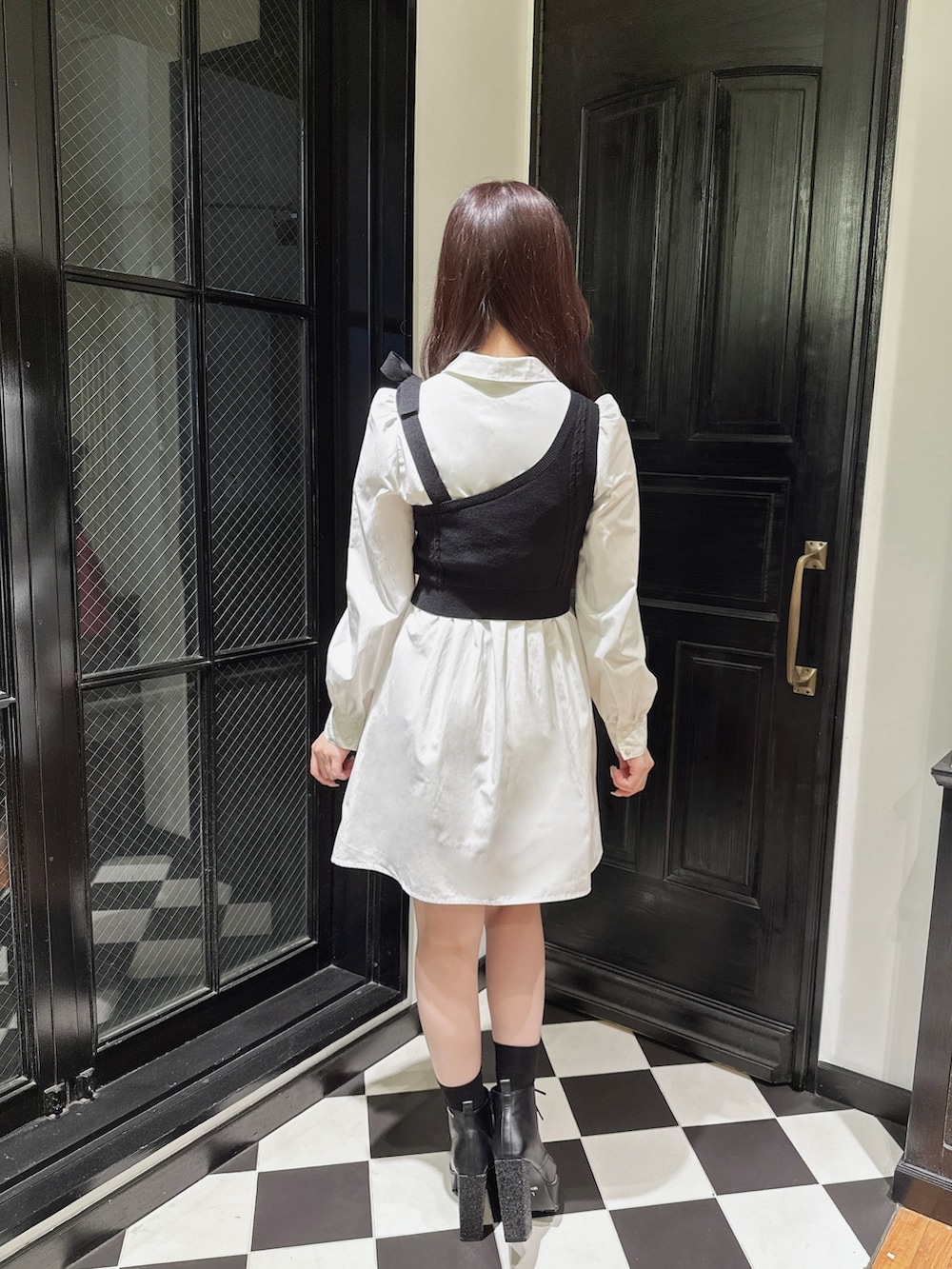 ホワイト系のワンピース、ブラック系のショルダーバッグ、ブラック系のブーツを着用したレディースの秋コーディネートの3枚目の写真