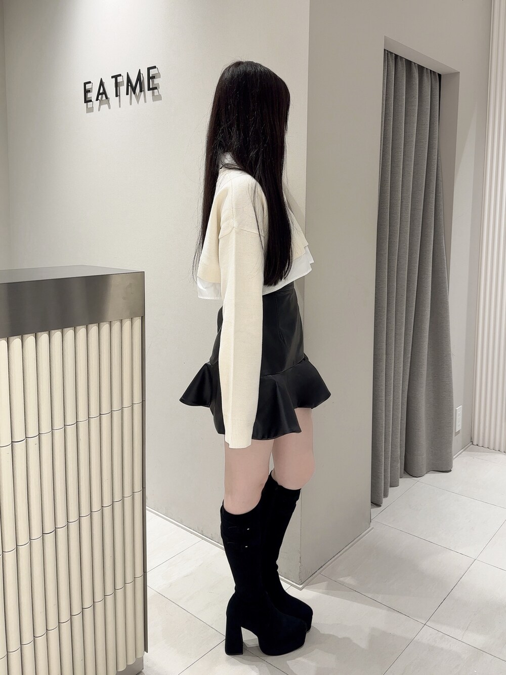 ブラック系のスカート、ホワイト系のシャツ/ブラウス、ブラック系のブーツを着用したレディースの秋コーディネートの2枚目の写真