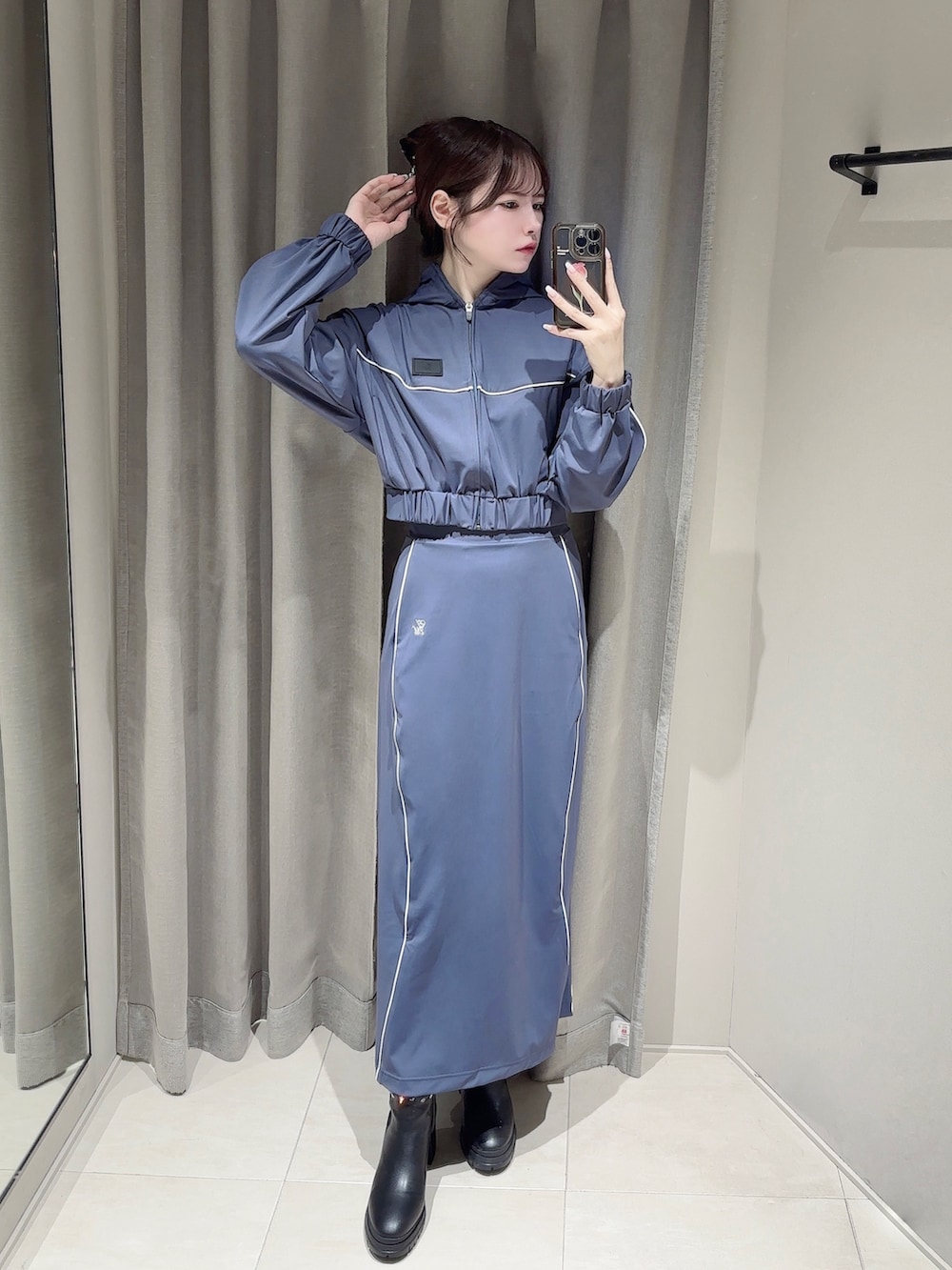 ブルー系のスカート、ブラック系のブーツ、ブルー系のナイロンジャケットを着用したレディースの秋コーディネートの4枚目の写真