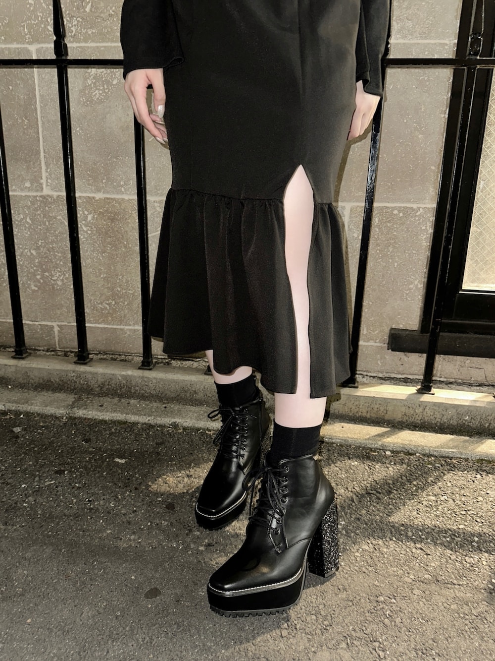 ブラック系のワンピース、ホワイト系のショルダーバッグ、ブラック系のブーツを着用したレディースの秋コーディネートの5枚目の写真