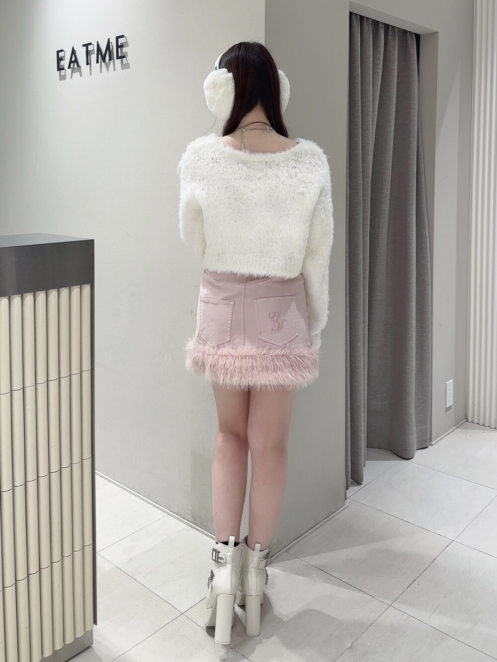 ピンク系のデニムスカート、ホワイト系のニット/セーター、ホワイト系のブーツを着用したレディースの冬コーディネートの4枚目の写真