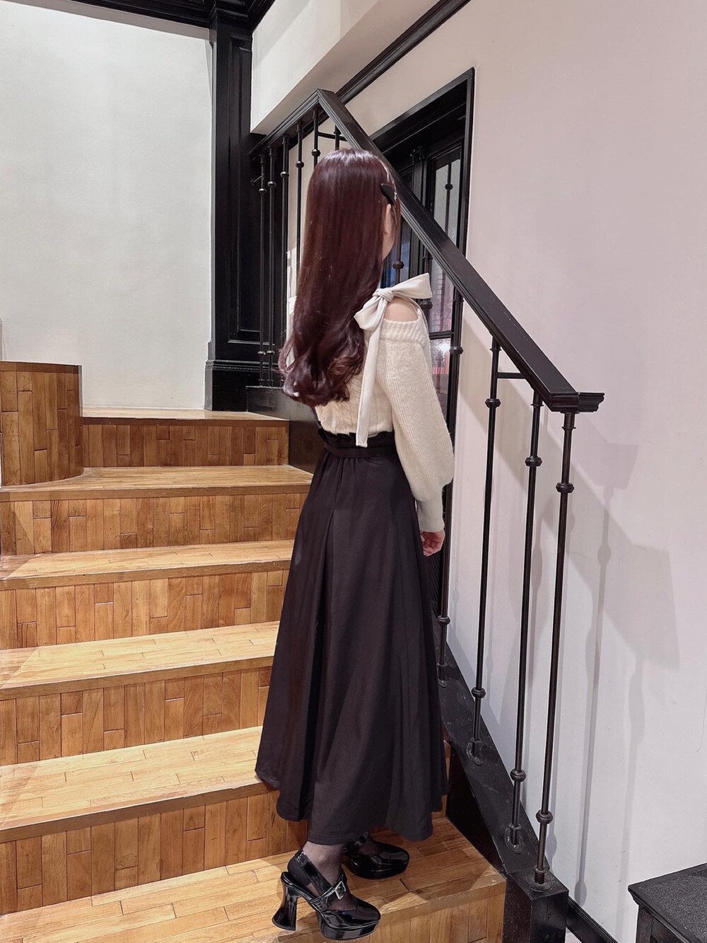 ホワイト系のニット/セーター、ブラック系のパンプス、ブラック系のジャンパースカートを着用したレディースの秋コーディネートの2枚目の写真