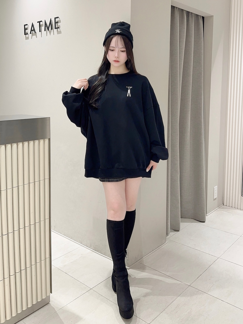 ブラック系のスウェット、ブラック系のデニムスカート、ブラック系のブーツを着用したレディースの秋コーディネートの2枚目の写真