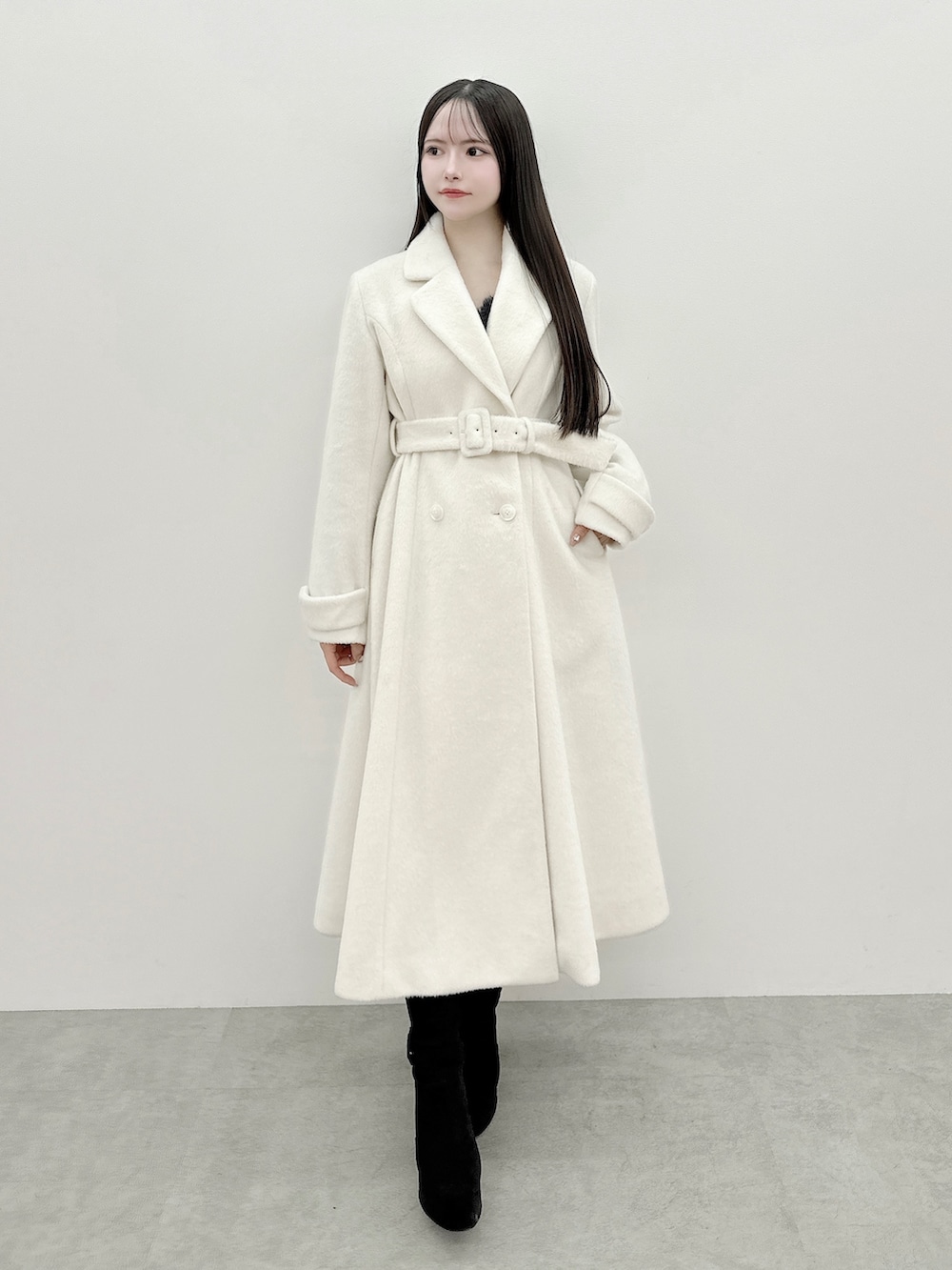 グレー系のワンピース、ホワイト系のその他アウター、ブラック系のブーツを着用したレディースの冬コーディネートの2枚目の写真