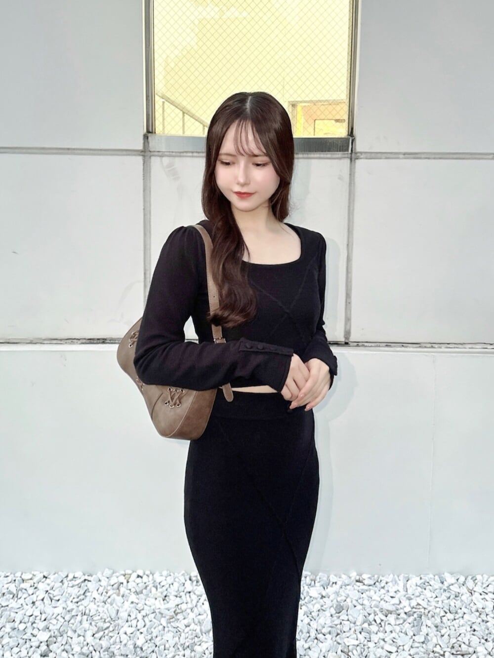 ブラウン系のショルダーバッグ、ブラック系のスカート、ブラック系のニット/セーターを着用したレディースの秋コーディネートの5枚目の写真