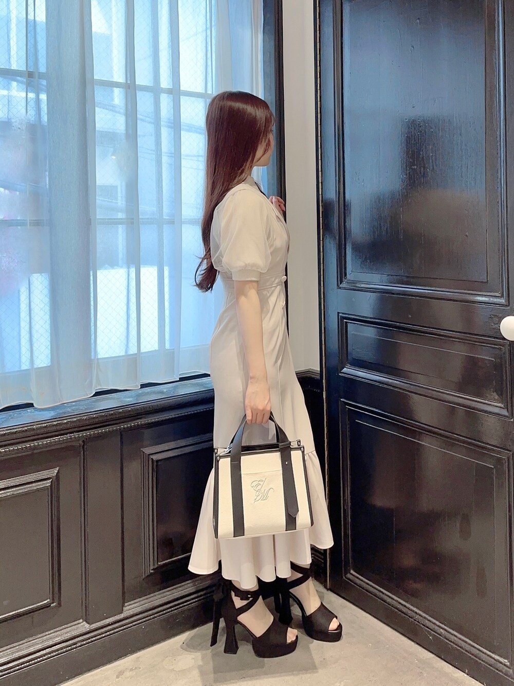 ホワイト系のニット/セーター、ホワイト系のスカート、ホワイト系のショルダーバッグを着用したレディースの春コーディネートの2枚目の写真