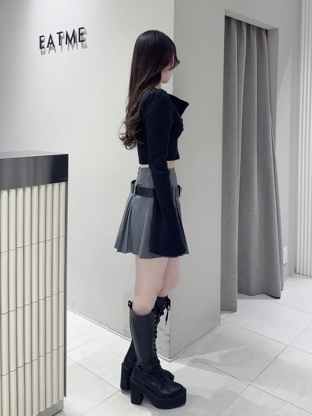 ブラック系のTシャツ/カットソー、グレー系のスカート、ブラック系のブーツを着用したレディースの冬コーディネートの3枚目の写真