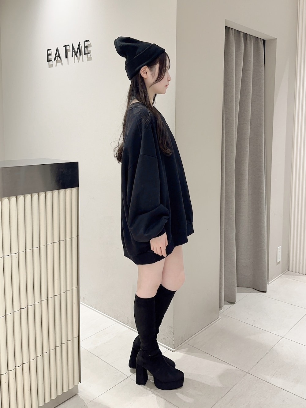 ブラック系のスウェット、ブラック系のデニムスカート、ブラック系のブーツを着用したレディースの秋コーディネートの3枚目の写真